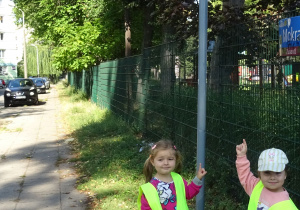 Dwie dziewczynki wskazują znak drogowy.