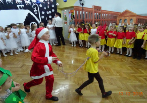 Na środku sceny znjduje się 2 chłopców. Jeden chłopiec przebrany jest za Mikołaja a drugi za renifera.