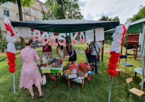 Stoisko z potrawami kuchni polskiej. Przy stoisku stoją dorosli.