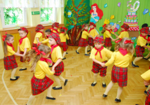 Na tle dekoracji z tortem i bajkowymi postaciami dzieci tańczą w parach Polkę Bałucką.
