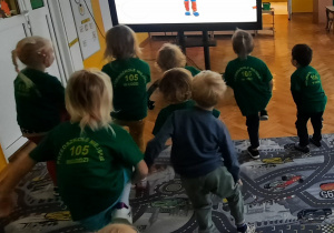 Przedszkolaki przy monitorze interaktywnym ćwiczą z liskiem.
