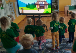Przedszkolaki przy monitorze interaktywnym ćwiczą z liskiem.