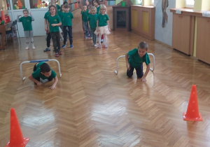 Przedszkolaki podczas zabaw sporowych z płotkami.